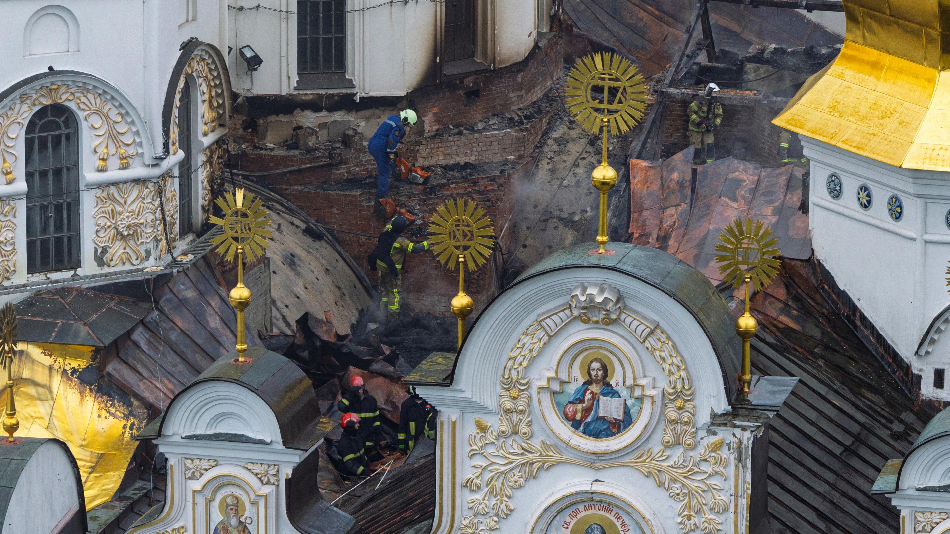 Ukrainian firefighters work at the roof of the damaged Dormition Cathedral