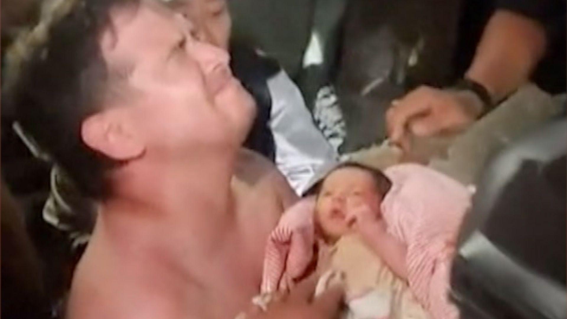 Emotional man holds baby wrapped in pink blanket