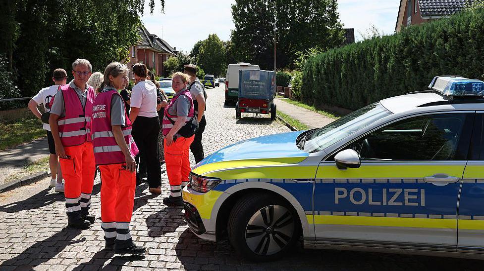 Police and members of a crisis intervention team speak to people near the scene where five people were killed in a shooting in Stade, northern Germany. Photo: 29 June 2026