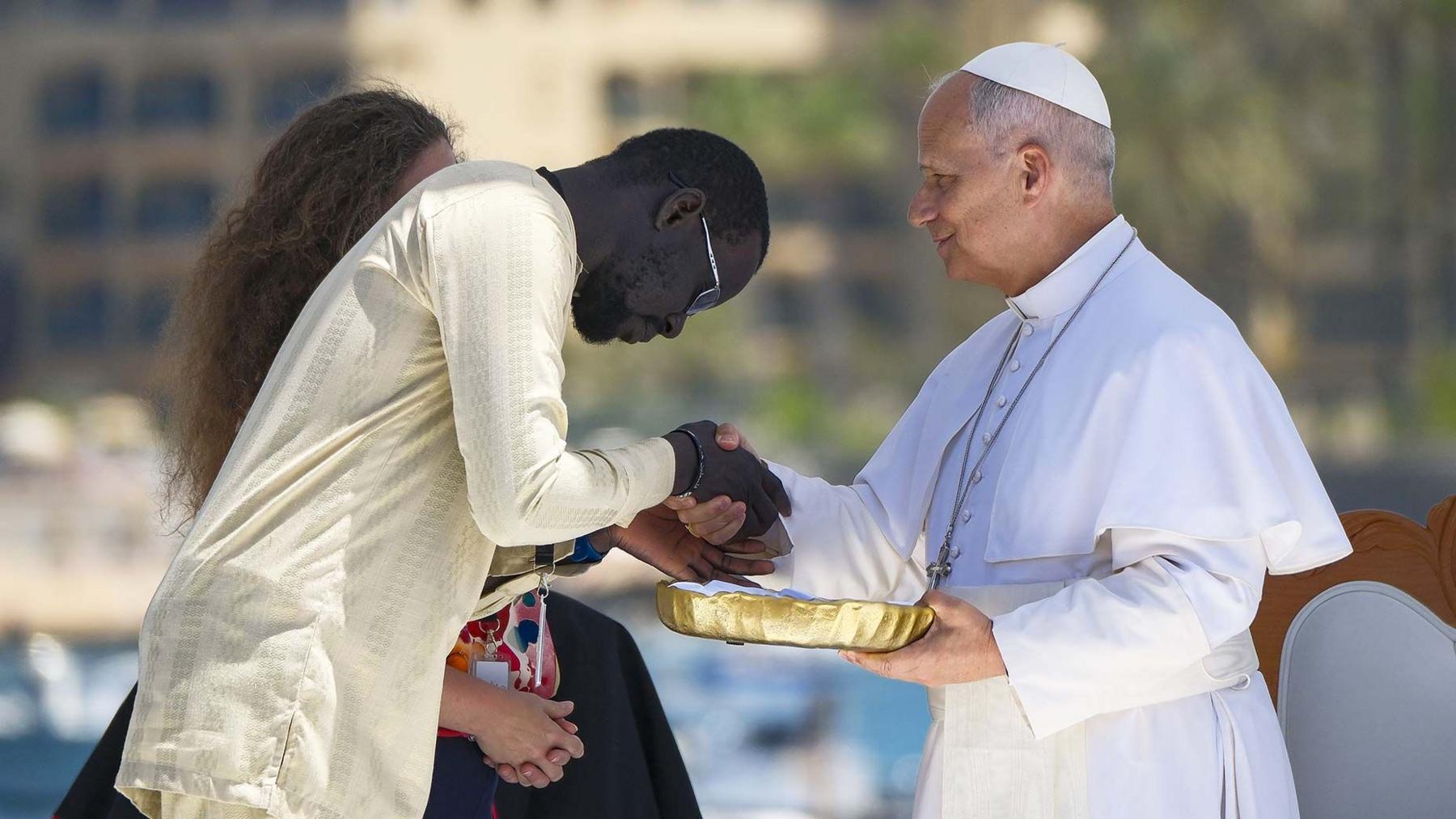Pope Leo XIV receives a present from a Senegalese migrant during a meeting at the Port of Arguineguin in Gran Canaria