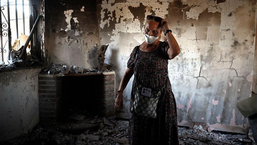 Concepcion Garcia enters her home for the first time after it was destroyed by a raging wildfire that swept through areas of the town of Navas del Rey, 55 kilometers southwest of Madrid, on July 29, 2026