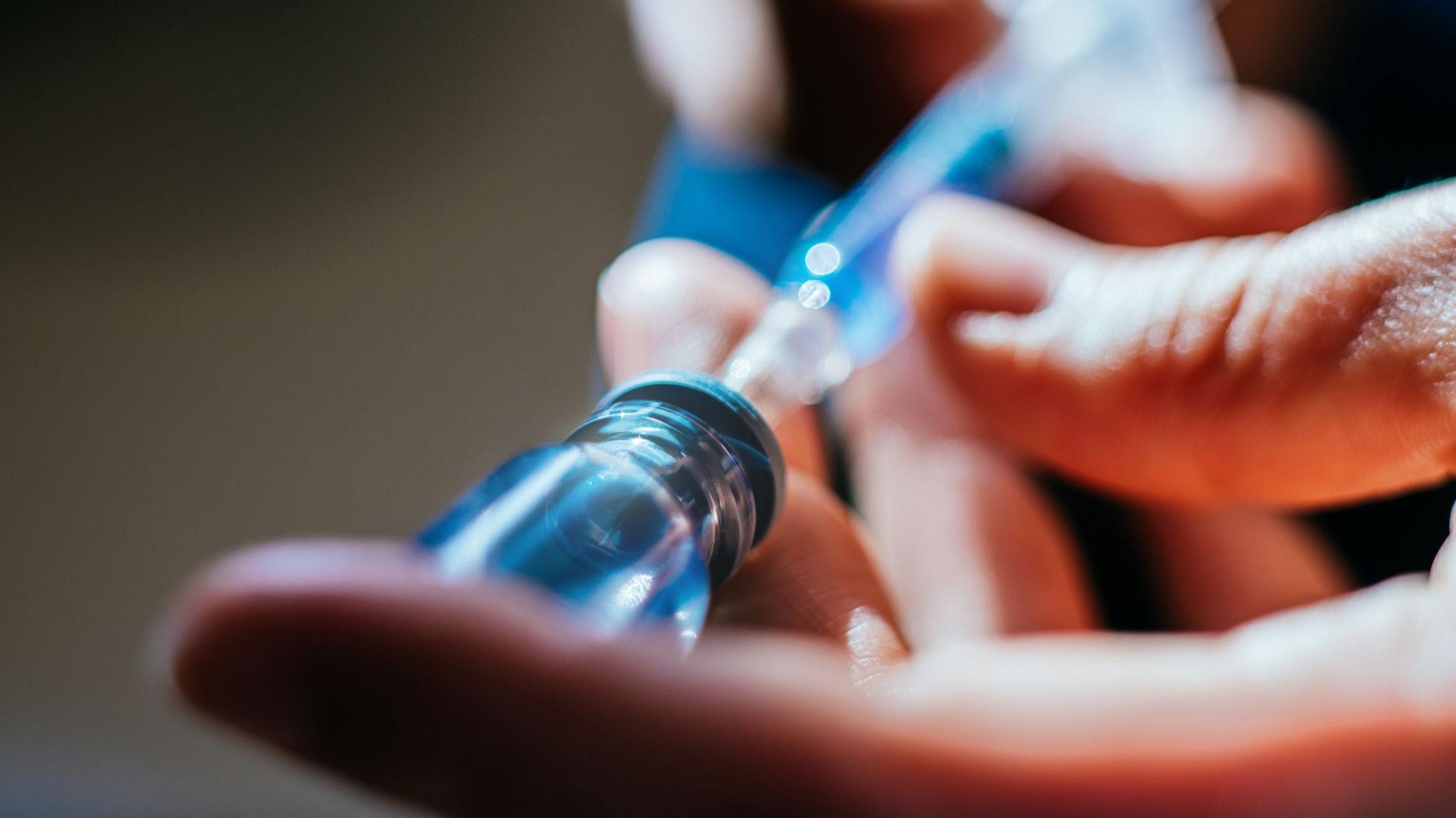 A close up of a person's hands as they prepare an injection