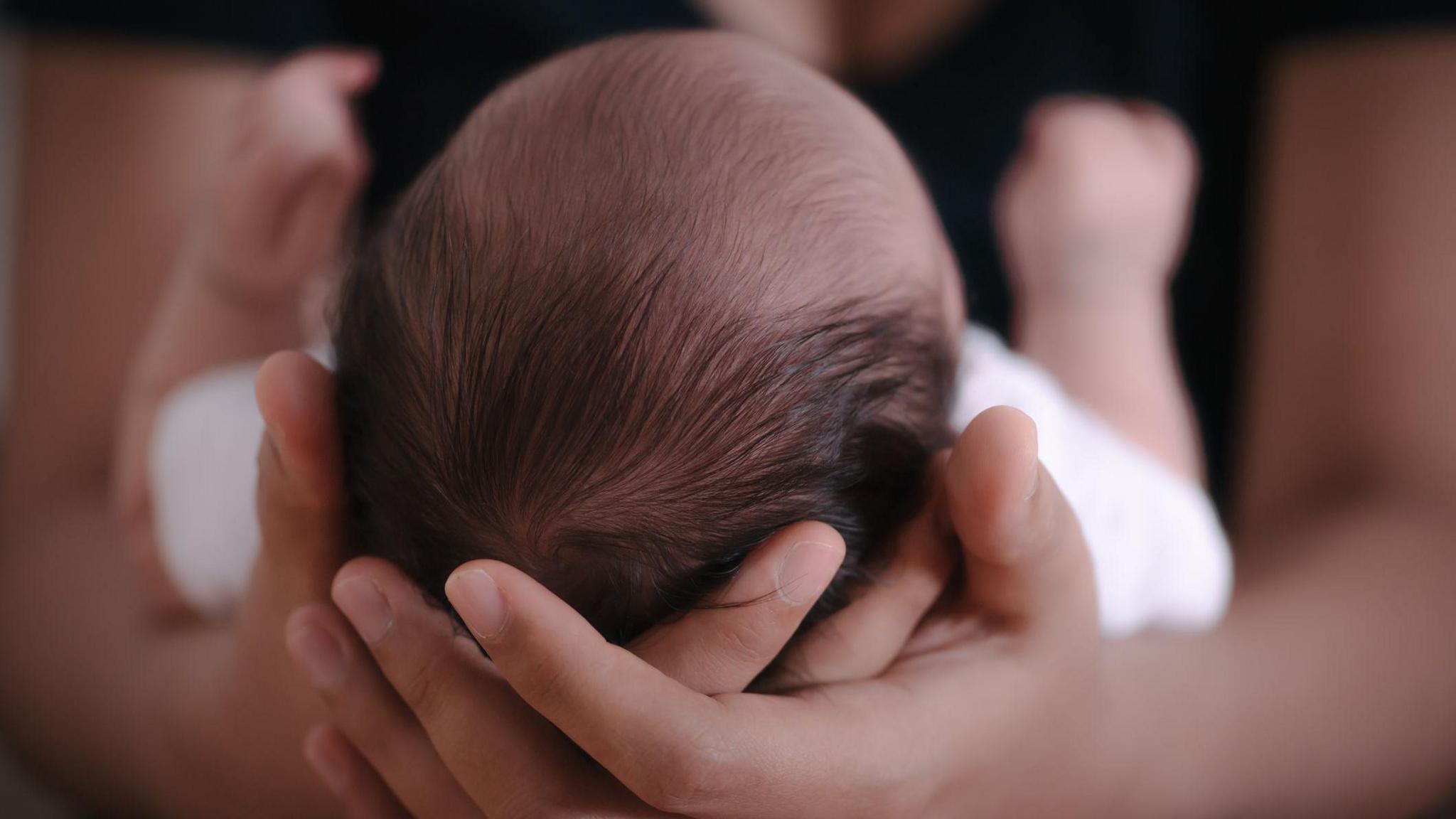Baby cradled in the arms of a mother.