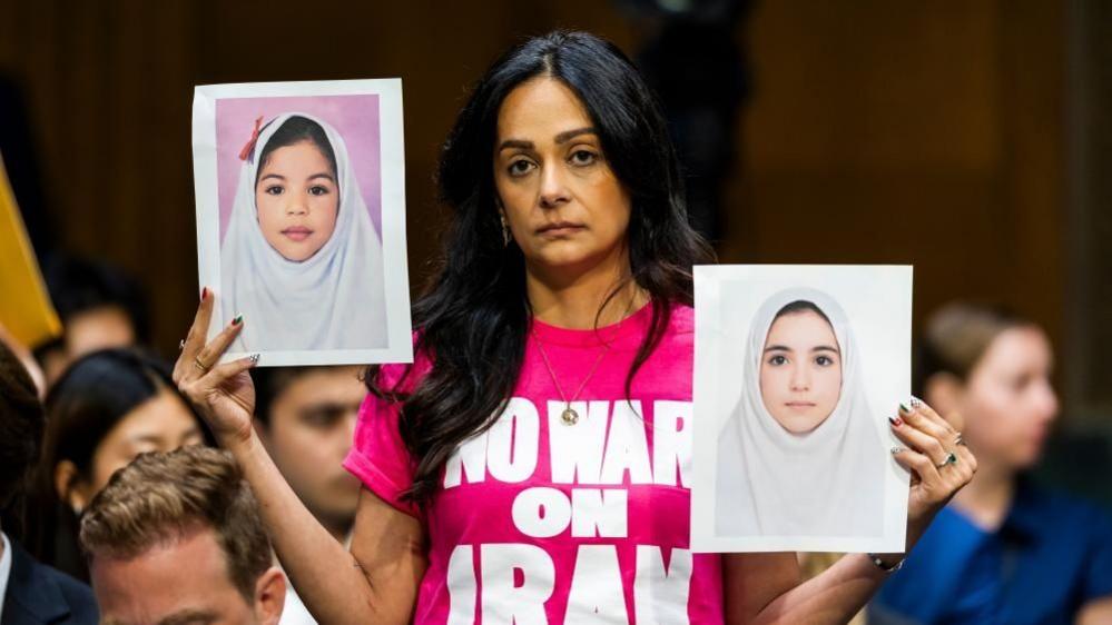 Protesters hold up pictures of Iranian girls at the Senate hearing for Secretary of Defense Pete Hegseth on 21 July 2026