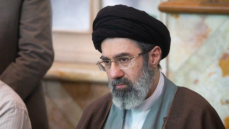 Mojtaba Khamenei, with a black turban and a brown robe, looks away from the camera