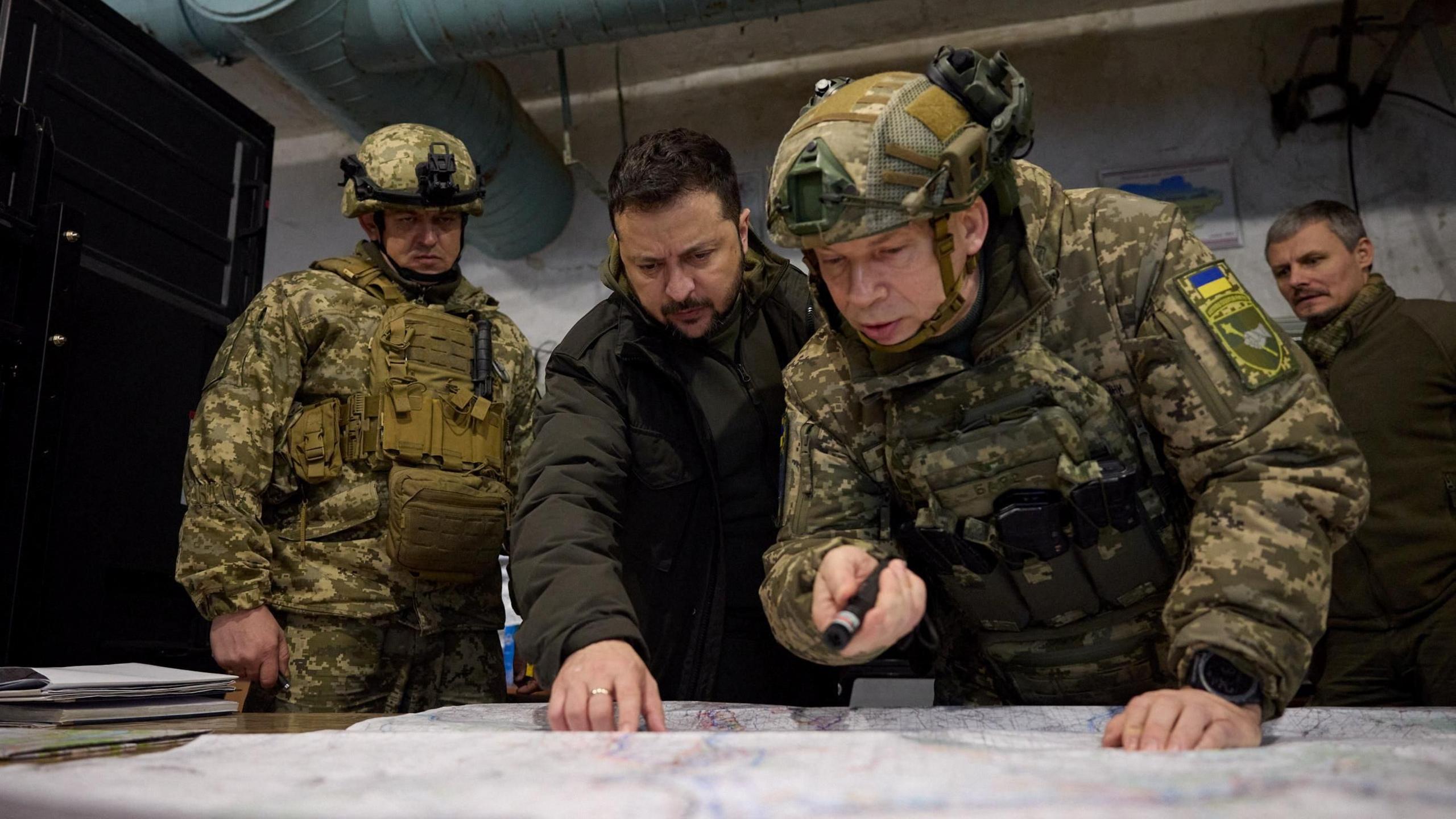 Ukraine's President Volodymyr Zelenskiy listens to Commander of the Ground Forces colonel general Oleksandr Syrskyi as he visits a position of Ukrainian servicemen in 2023