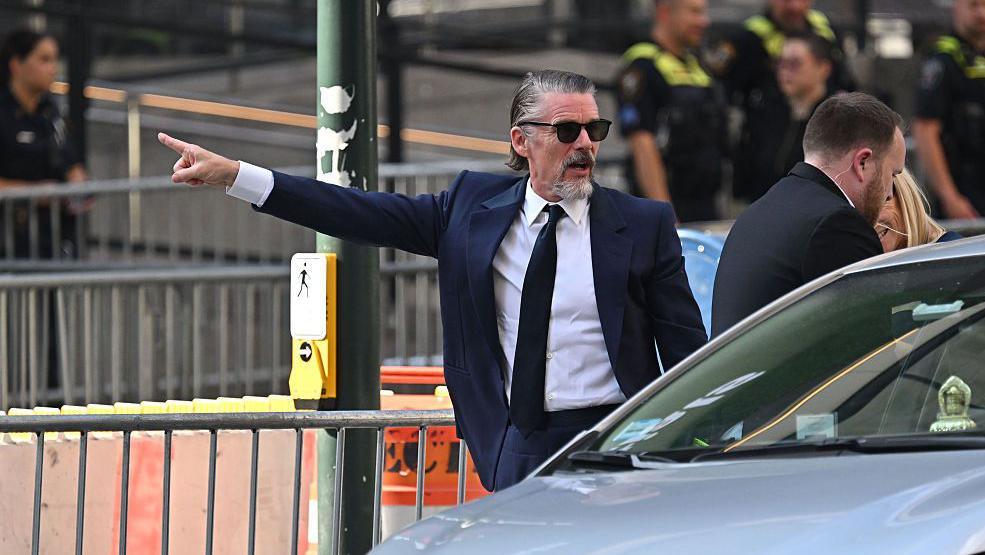 Ethan Hawke points his arm as he arrives at Madison Square Garden on 3 July.