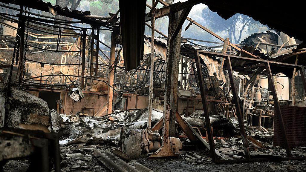 Charred remains of a home burned in the wildfires in the Madrid community. Burned out chairs and beds and fabric litter the floor