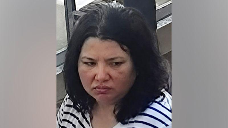 A woman with dark hair and a serious expression looks down. She wears a striped black and white shirt.