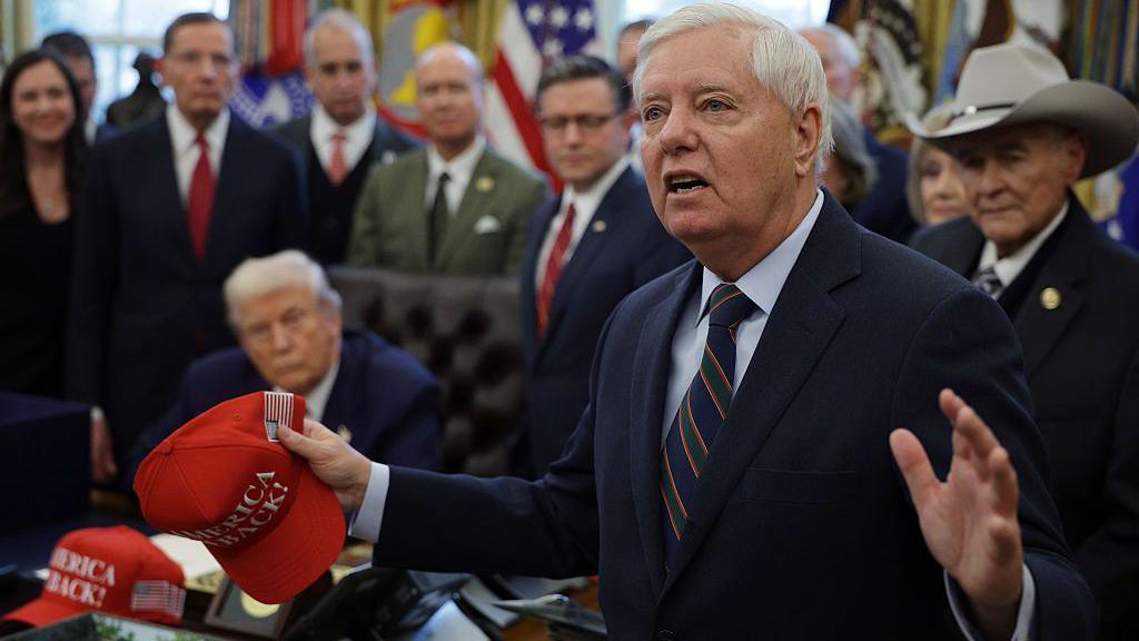 Lindsey Graham speaks during a bill signing in the Oval Office. President Donald Trump can be seen in the background