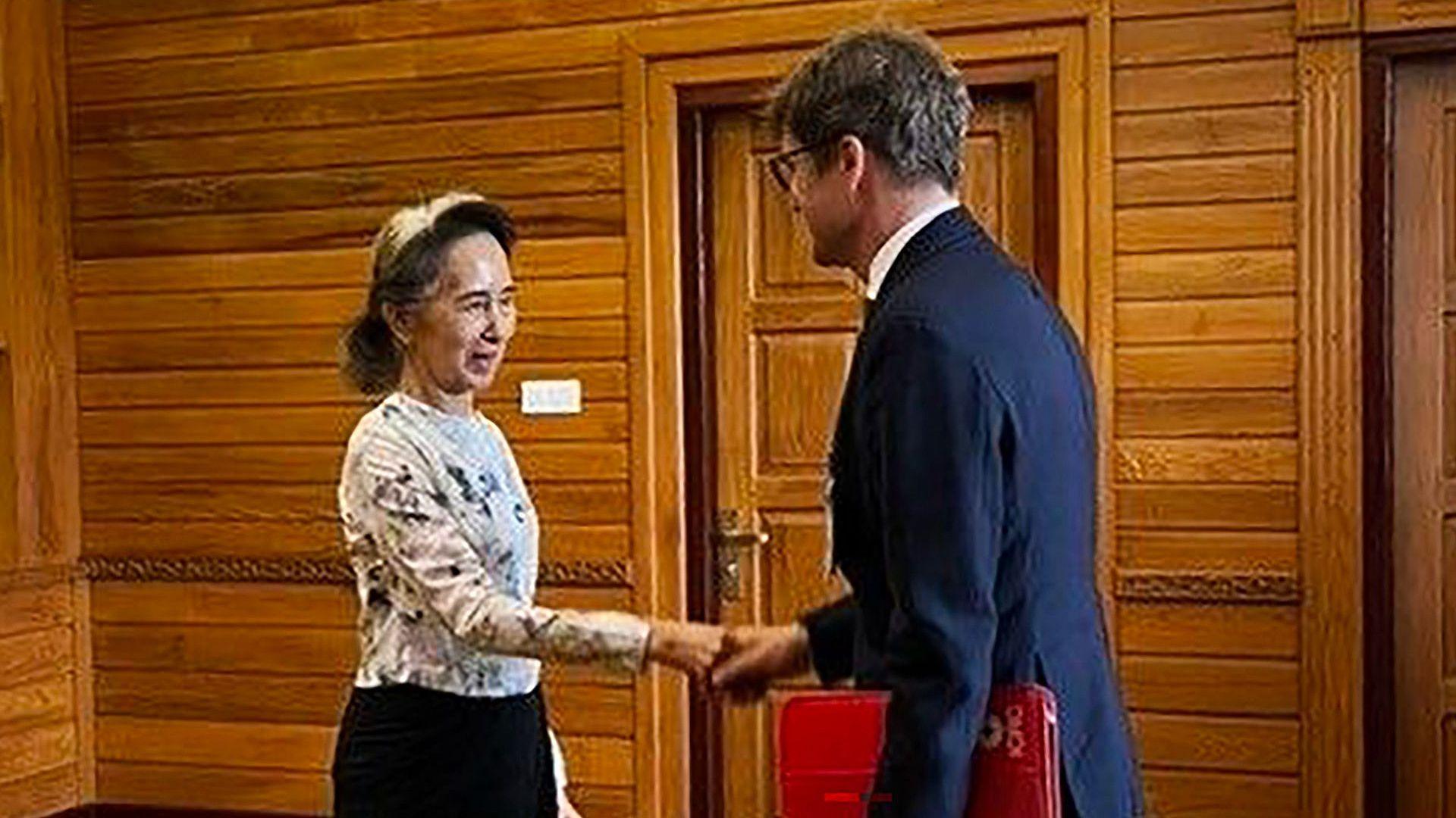 Former Myanmar president Aung San Suu Kyi shakes hands with Arnaud de Baecque, resident representative of the International Committee of the Red Cross (ICRC)