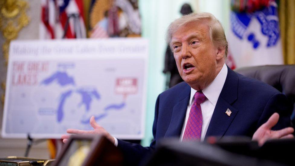 Trump in Oval Office with map of Lake Ontario behind