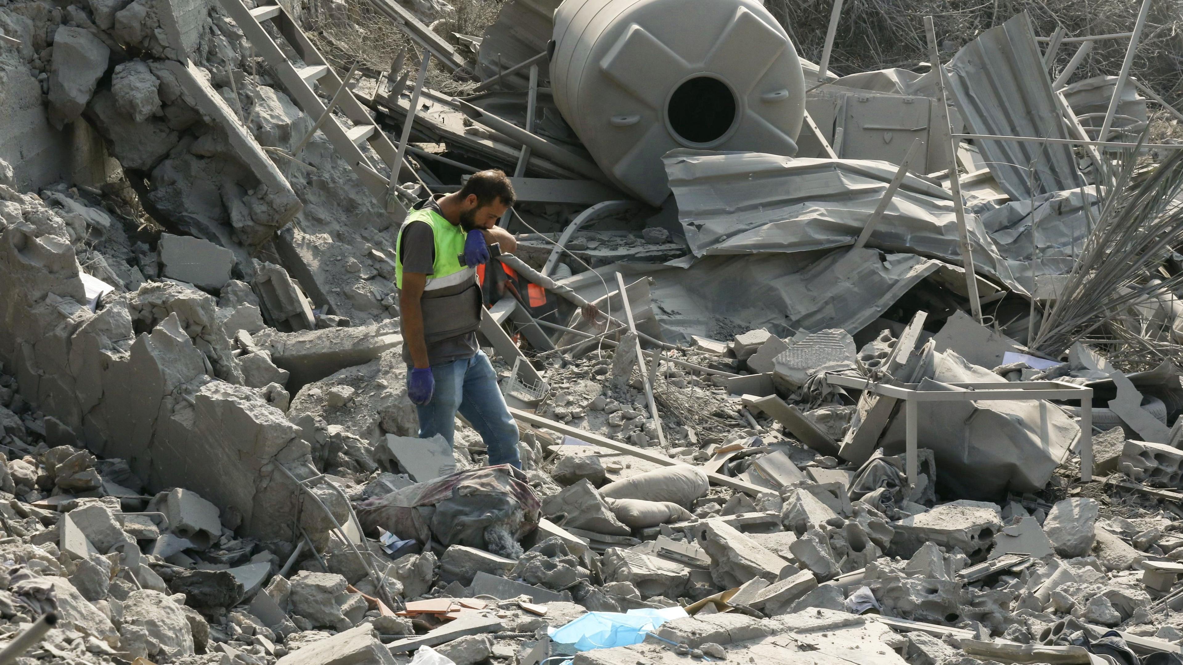 An emergency worker looks through rubble in the aftermath of an airstrike on Ansar in Lebanon