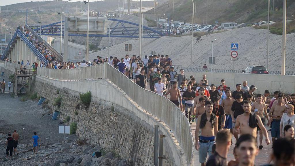 Dozens of migrants walking on a coastal path