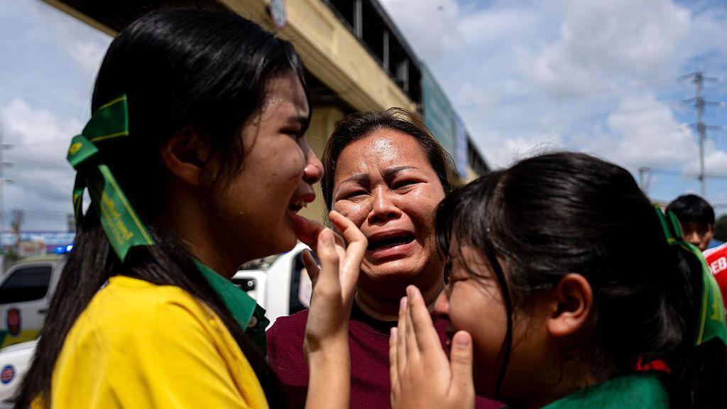 Two schoolgirls and a woman bursting into tears