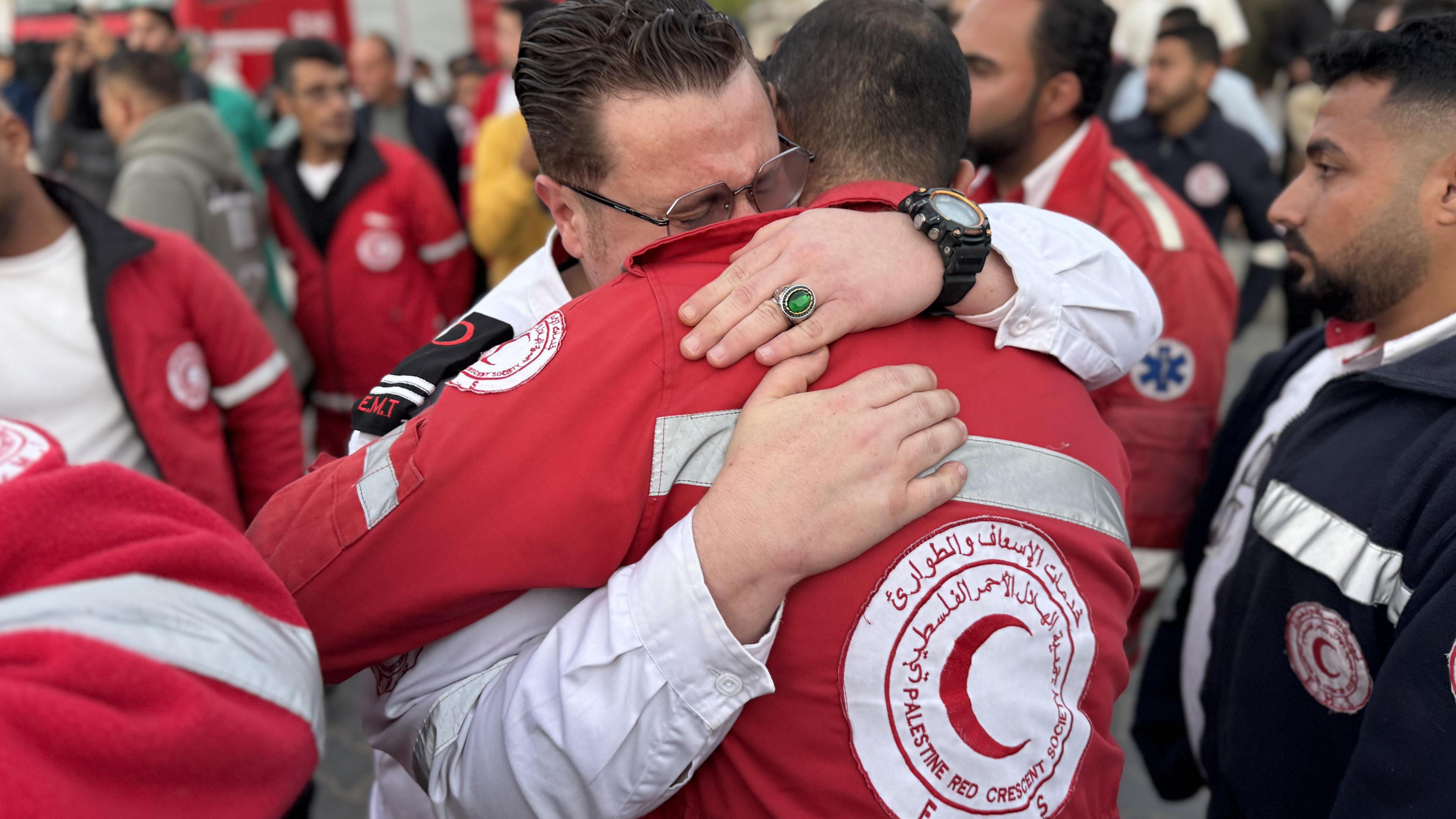 Palestinian Red Crescent Society employees embrace as the bodies of their colleagues are brought to a medical facility in Khan Younis, southern Gaza. Photo: 30 March 2025