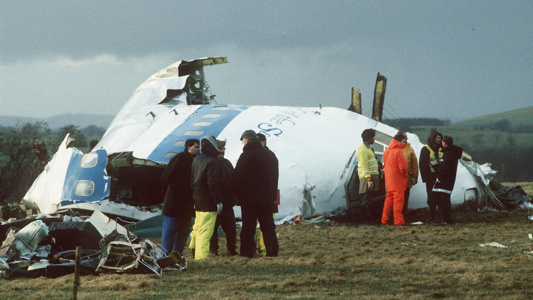 Emergency service workers stand next to the wreckage of Pan Am flight 103 in a field east of Lockerbie.