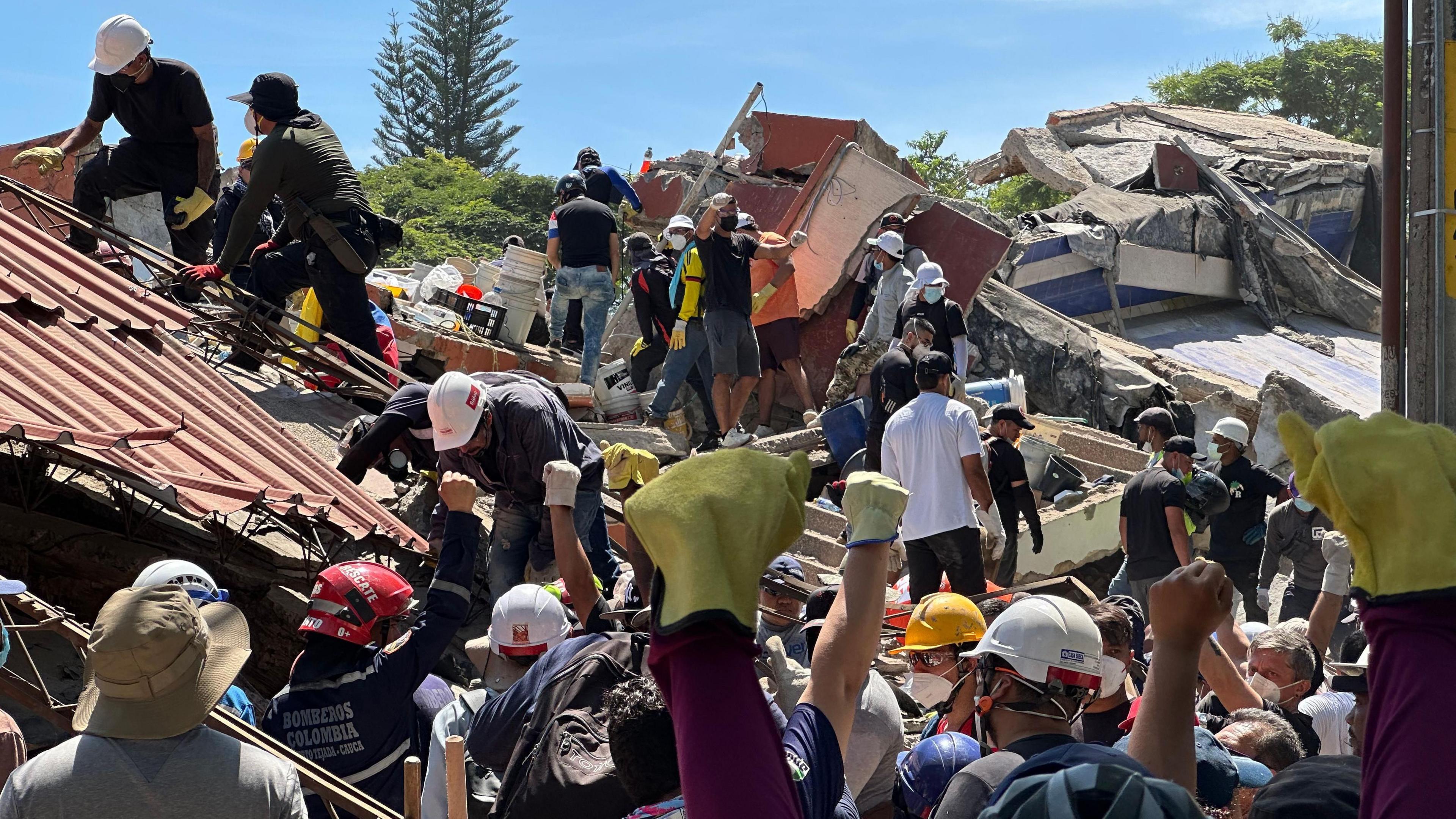 Rescue workers and volunteers at the site of a collapsed building in Cali