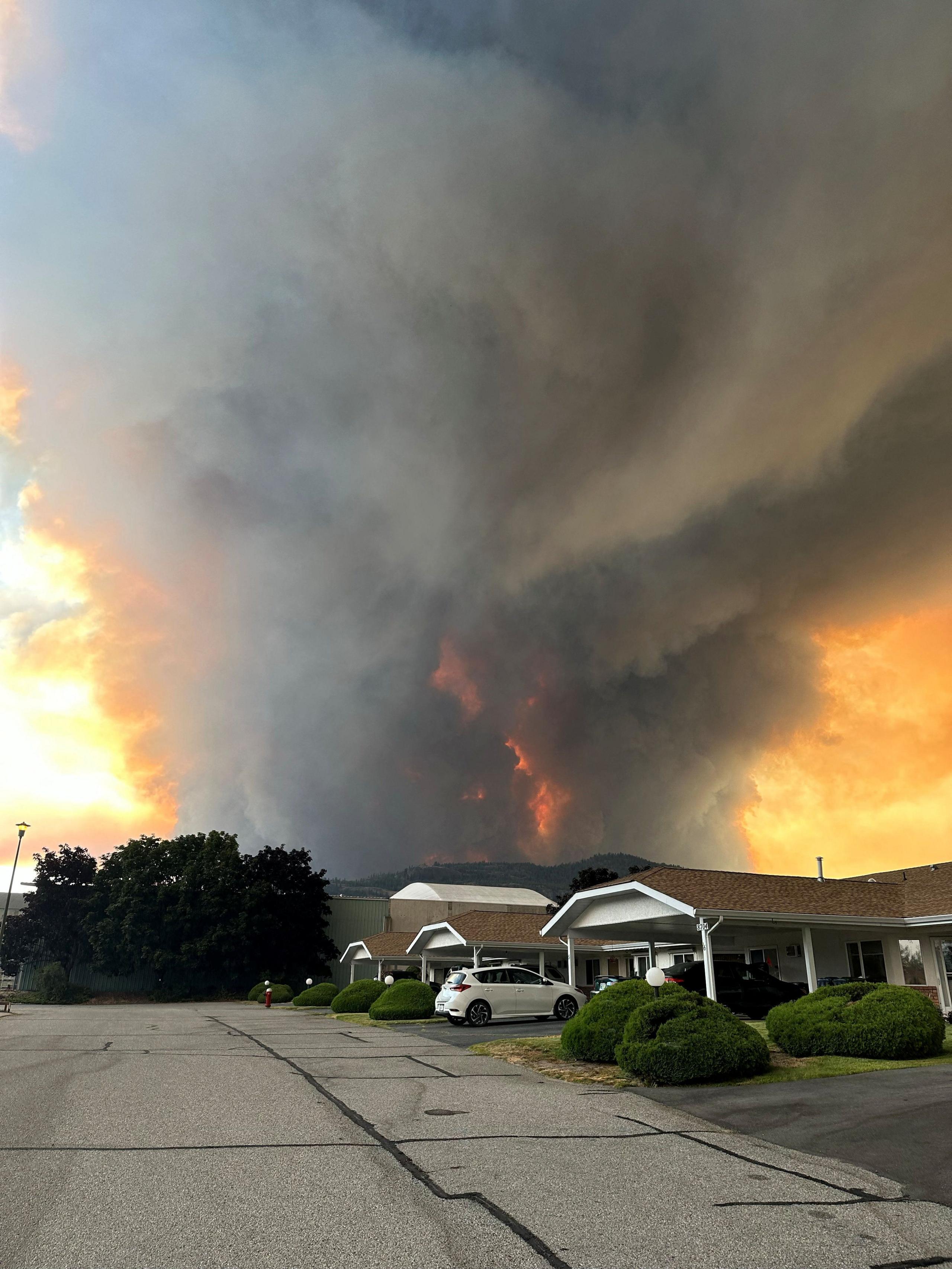 Smoke rises from the Bald Range wildfire over a residential street in Summerland