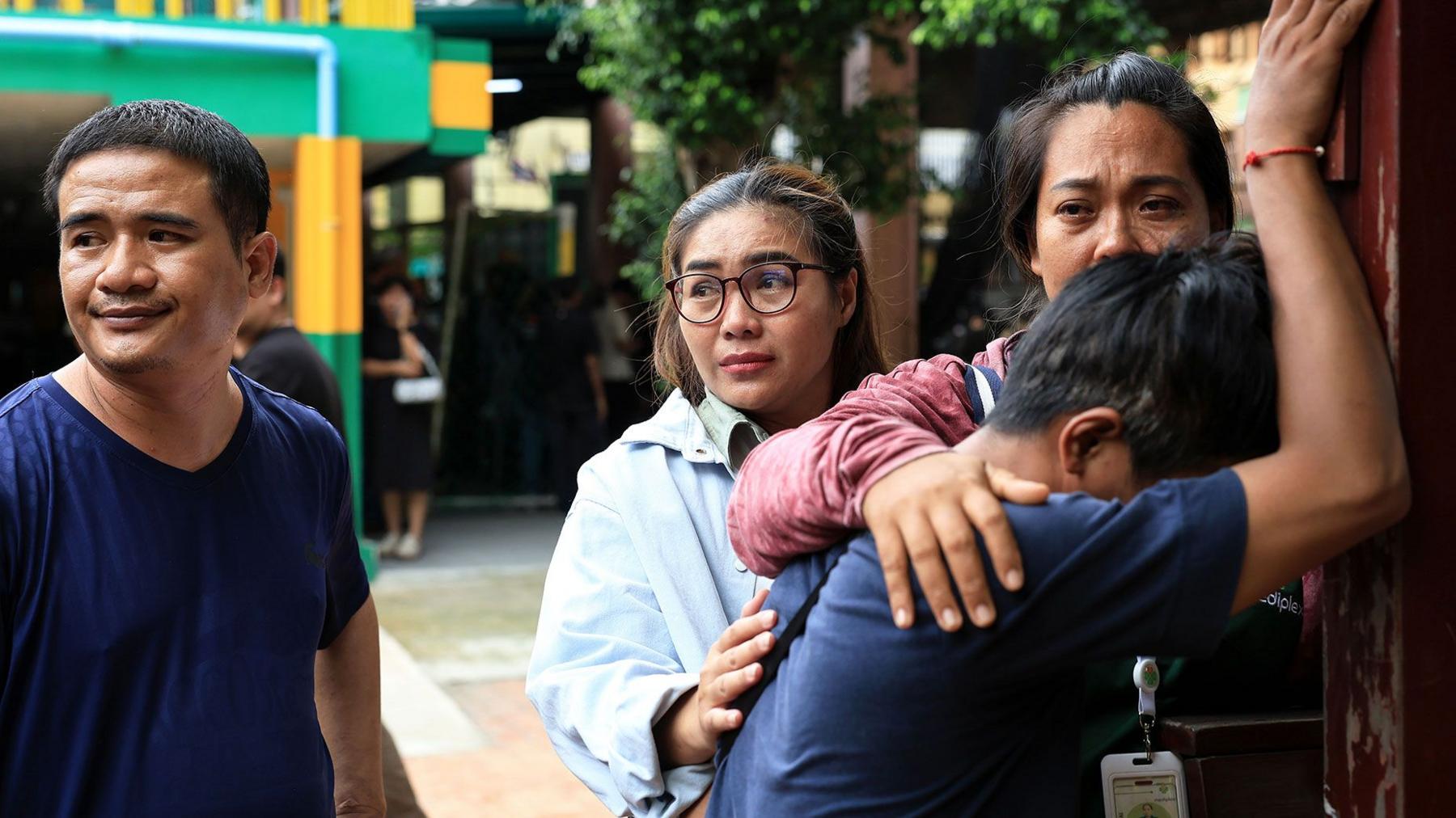 A person close to one of the victims reacts by leaning their head against a wall and people nearby to comfort him.