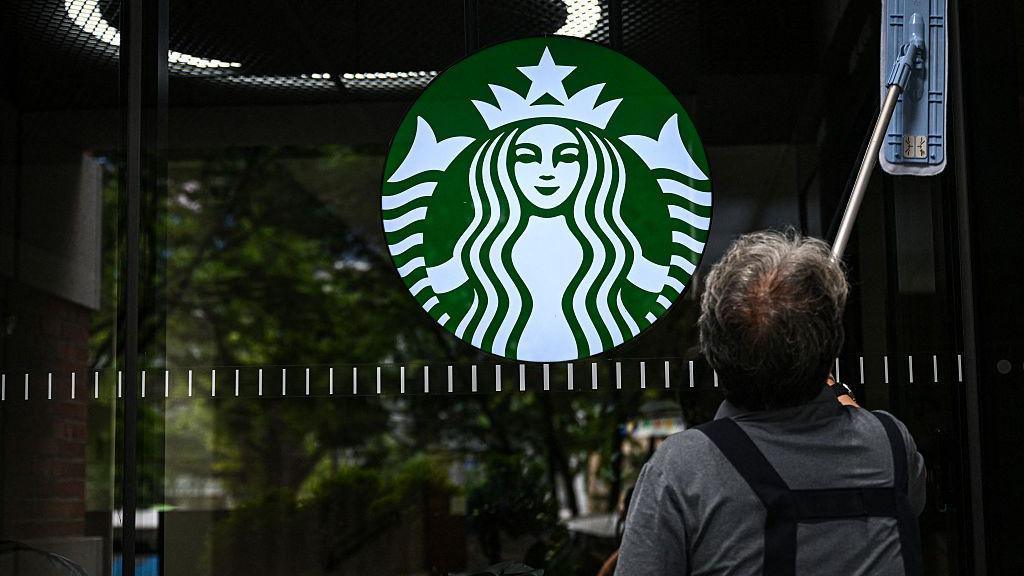 A cleaning lady wipes the window of a Starbucks coffee shop