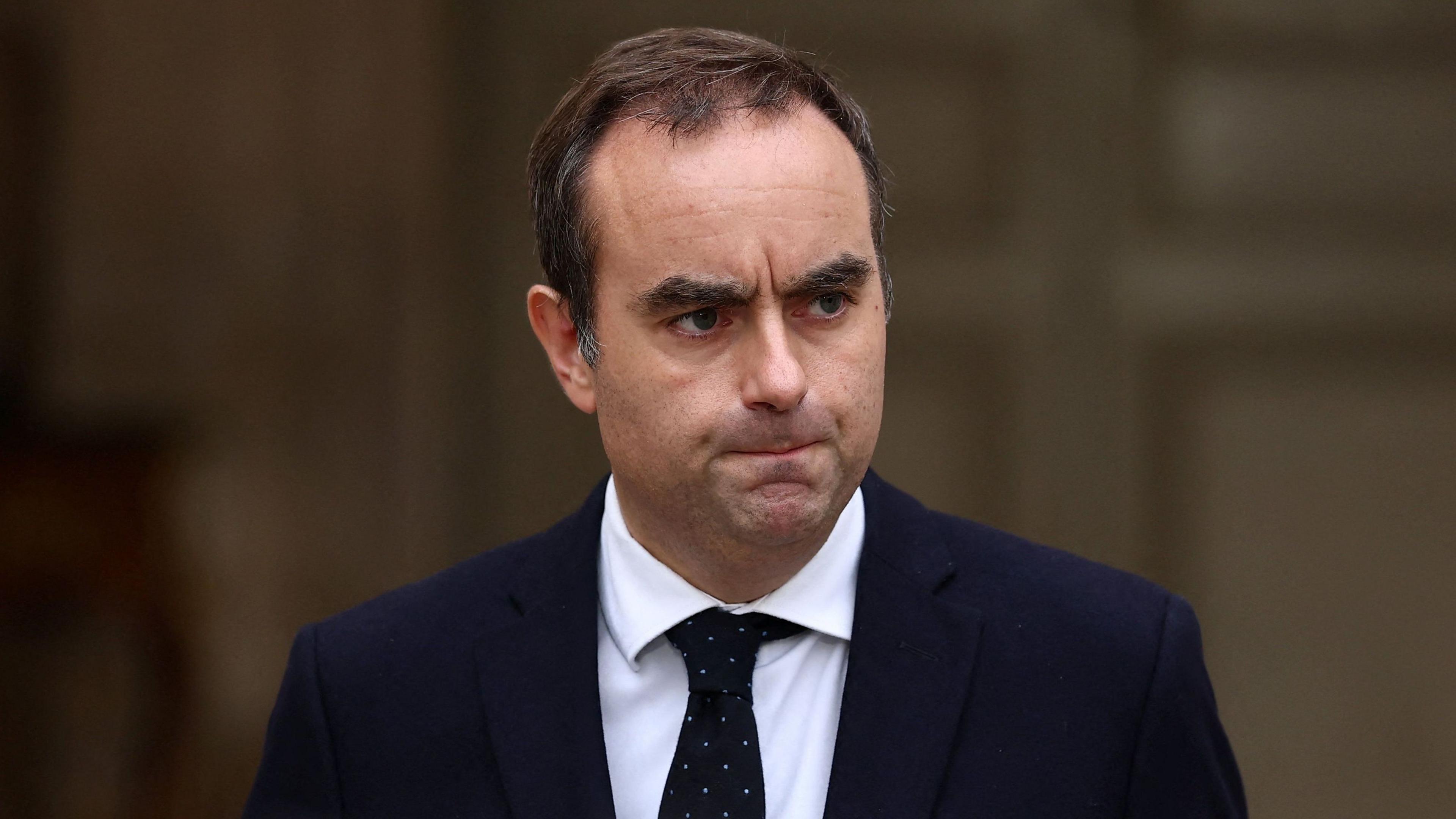 Prime Minister Sebastien Lecornu, who has brown hair and wears a navy suit with white shirt and black tie, arrives to deliver a statement at the Hotel Matignon in Paris in October last year