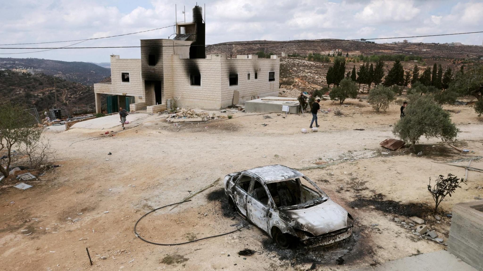 Israeli security forces and journalists inspect a destroyed car and a fire-damaged home belonging to the al-Tubasi family, following an Israeli settler attack in Jalud, in the occupied West Bank (29 September 2026)