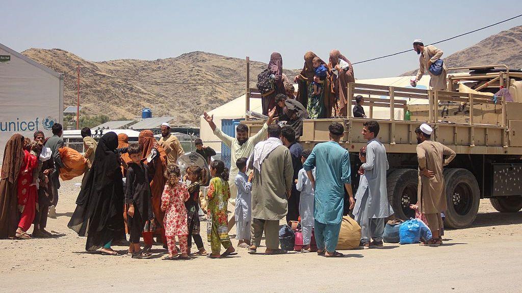 This photograph taken on June 24, 2026 shows Afghan returnees deported from Pakistan, climbing down a militray truck upon their arrival at Omari camp near the Afghanistan-Pakistan zero point border crossing in Torkham, Nangarhar province.