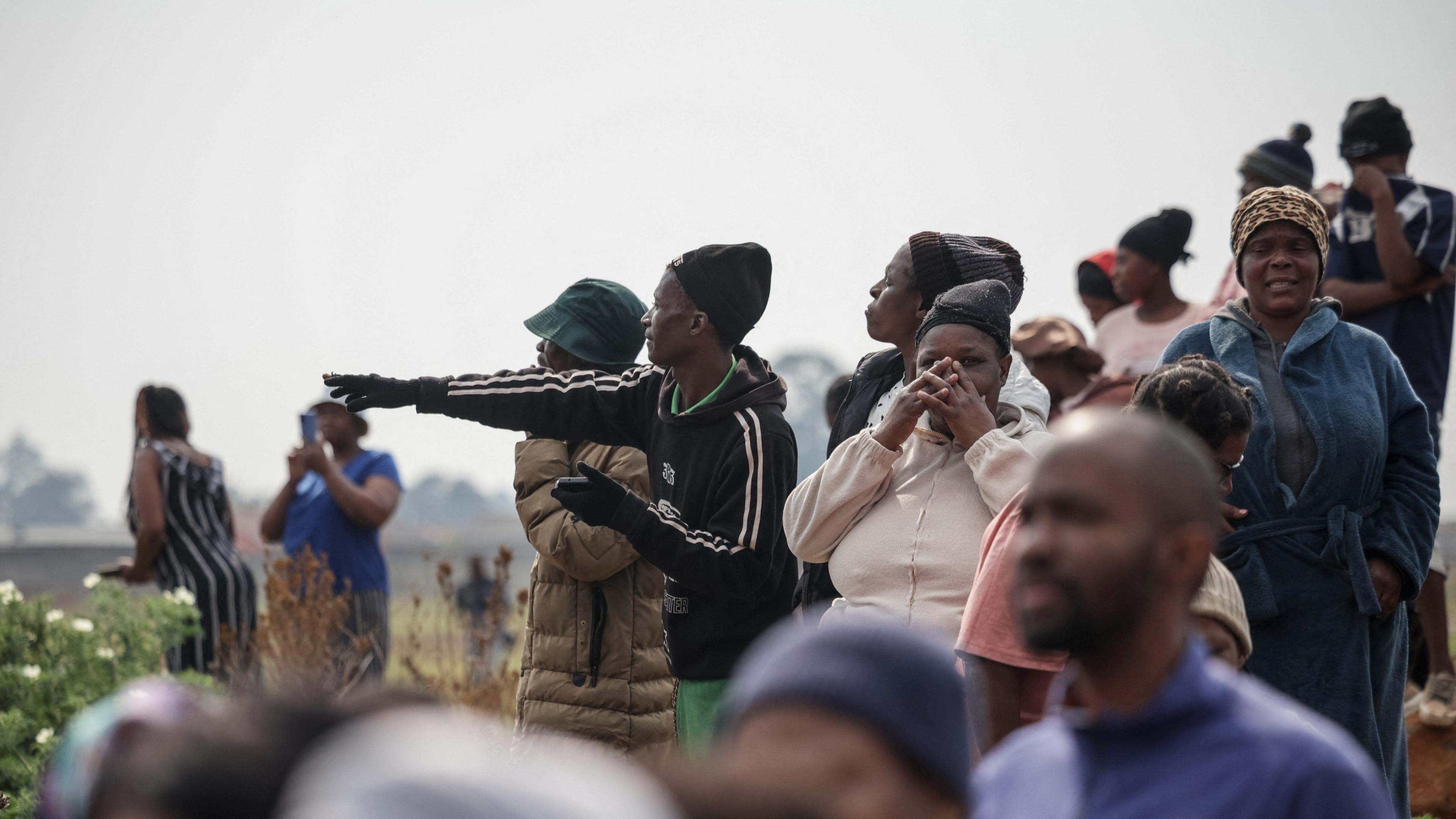 A group of people gathered near the site where the body was found. One woman is pointing