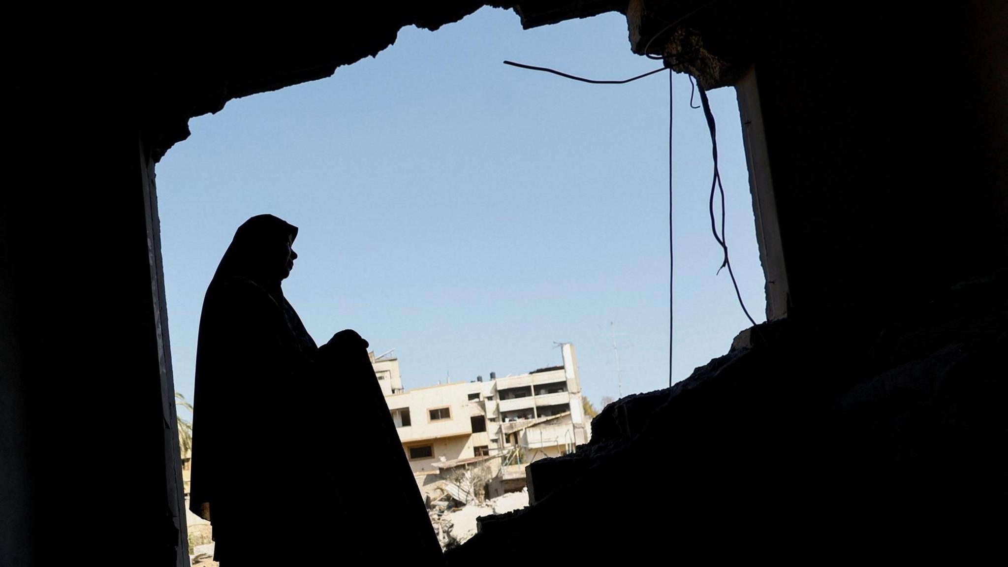 A file photo showing a Palestinian woman inspecting her damaged home after an Israeli strike on a nearby mosque, in Gaza City (29 July 2026)