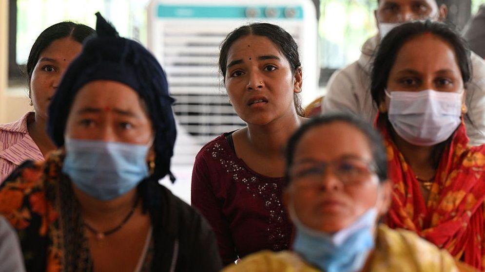 Women looking at a screen to identify loved ones who have died at a mortuary in Nepal