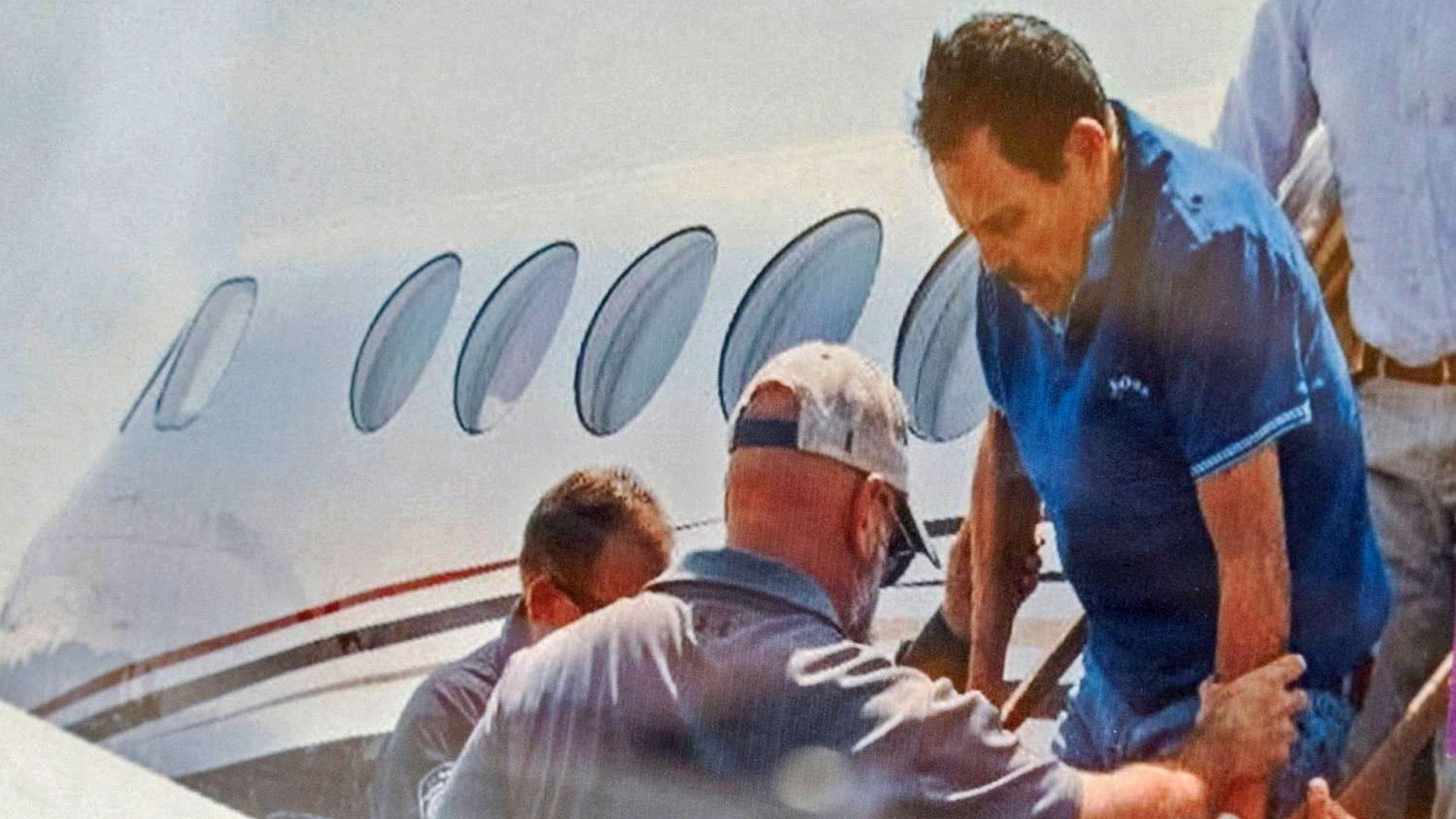 Zambada, in a blue golf shirt, is helped off a small plane while being taken into custody in July 2024