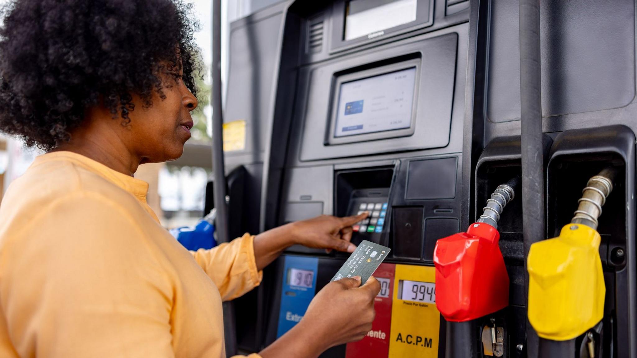 A woman pays for fuel at a gas station with her bank card