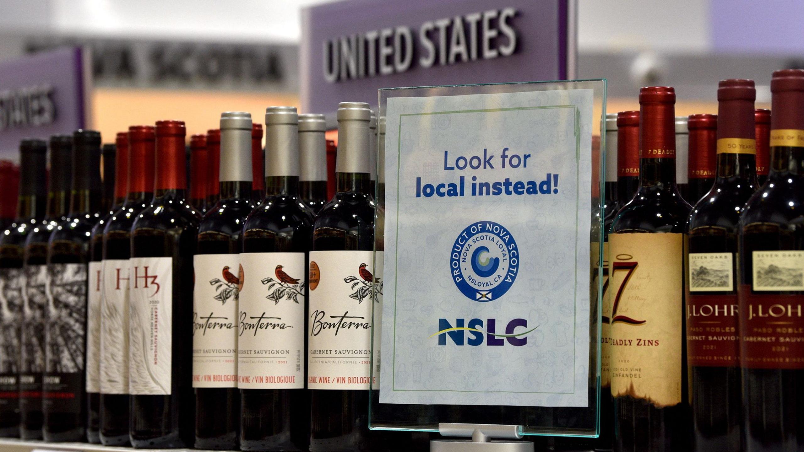 A "Look for local instead" sign displayed on a shelf with wine at a Canadian liquor shop.