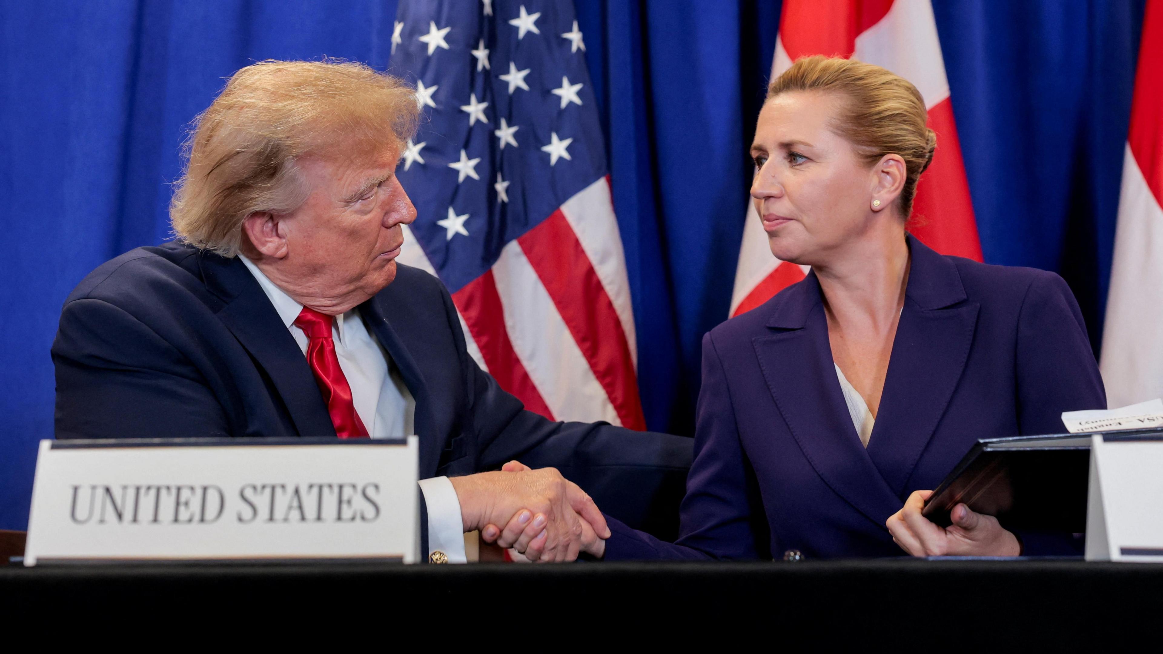 US President Donald Trump shakes hands with Danish Prime Minister Mette Frederiksen as they attend a trilateral signing event