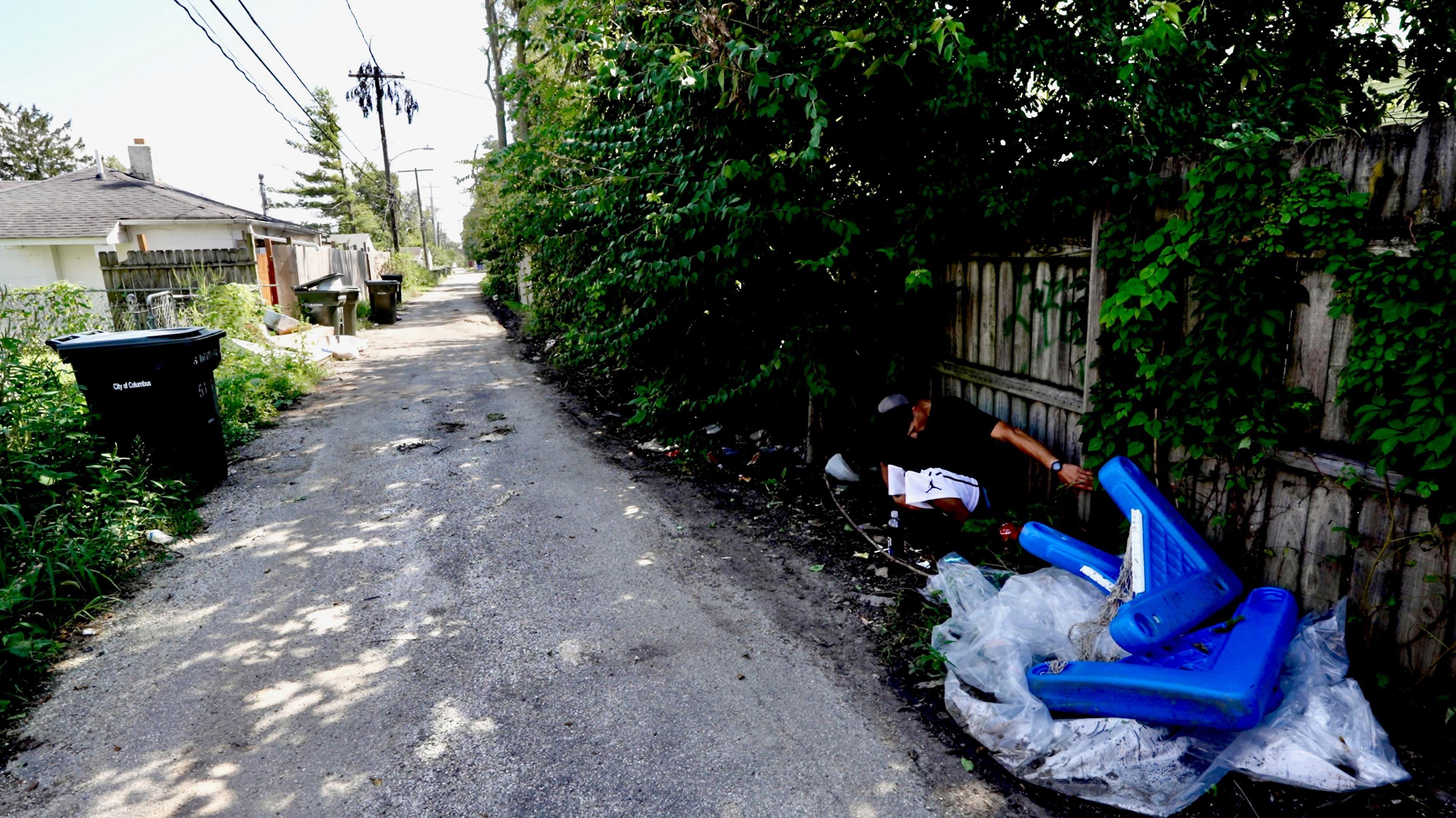 An alleyway with Mike crouched on the ground on the right-hand side