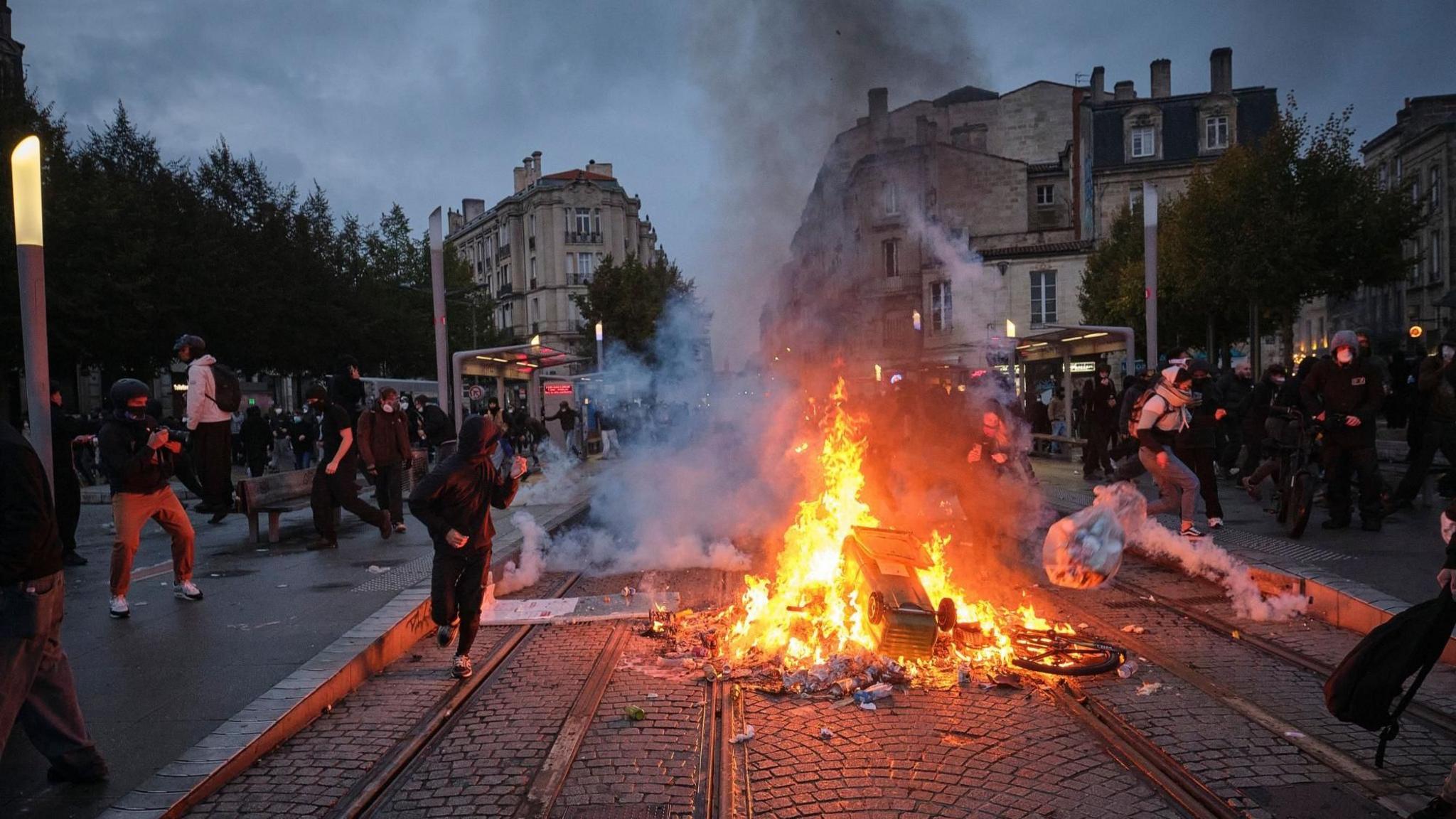 People clash with police officers as objects burn at a barricade during a demonstration against the high cost of living in Bordeaux, France, 24 October 2026.