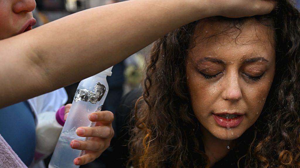 A protester cleaning tear gas from the eyes of another female demonstrator