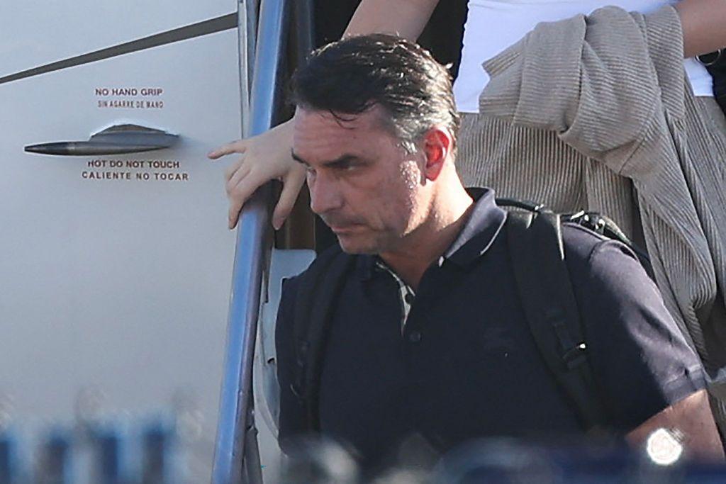 Bolsonaro in a dark shirt carrying a backpack as he leaves a plane