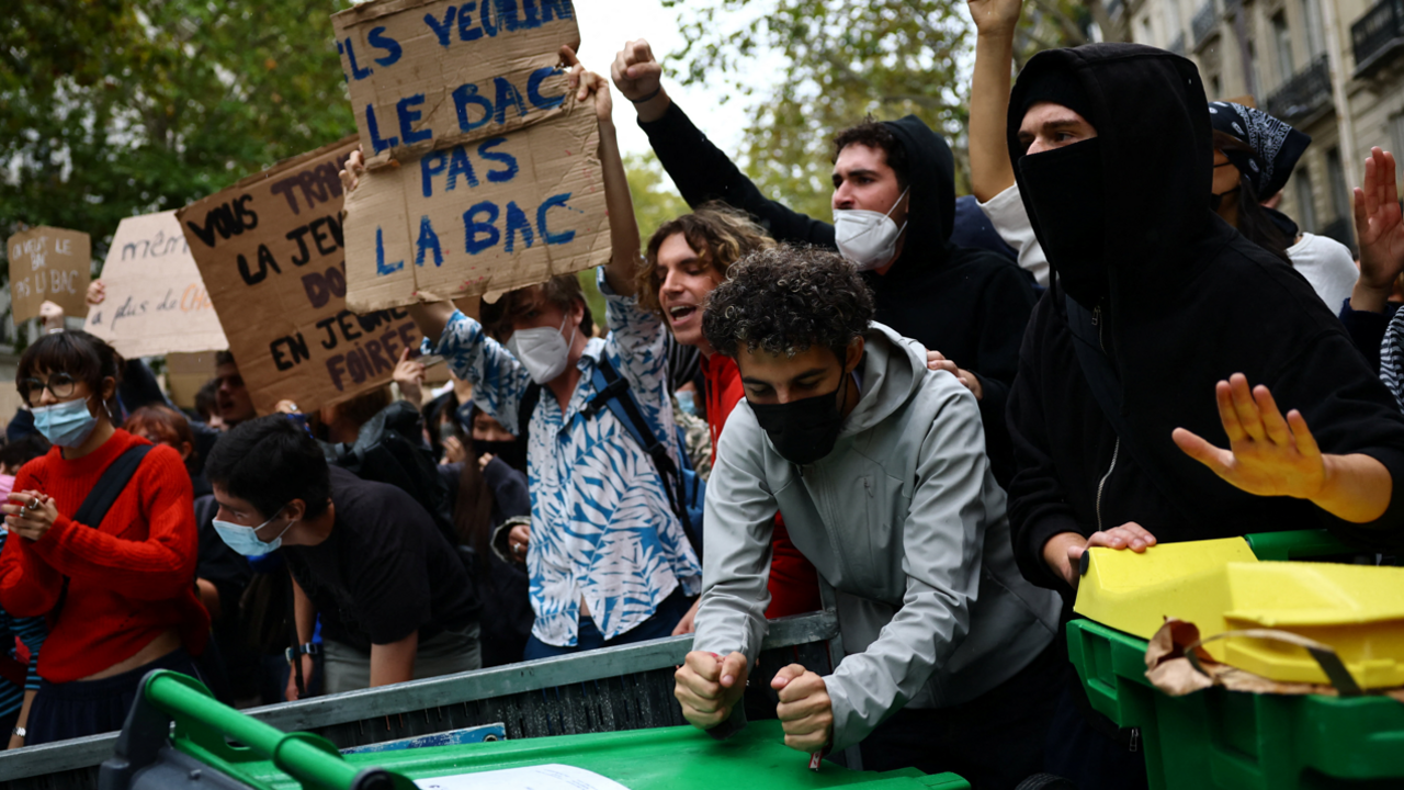 Protesters hold placards behind a barricade to block in Paris, 7 October