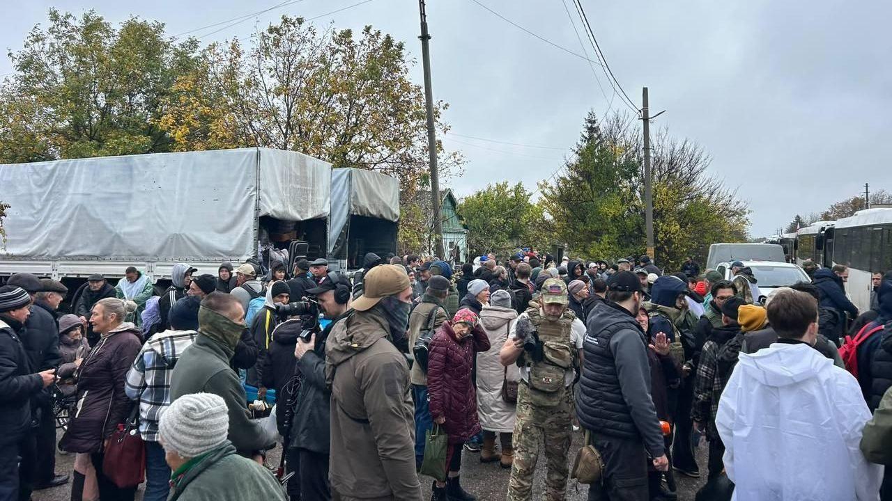 A crowd of people waiting to board buses