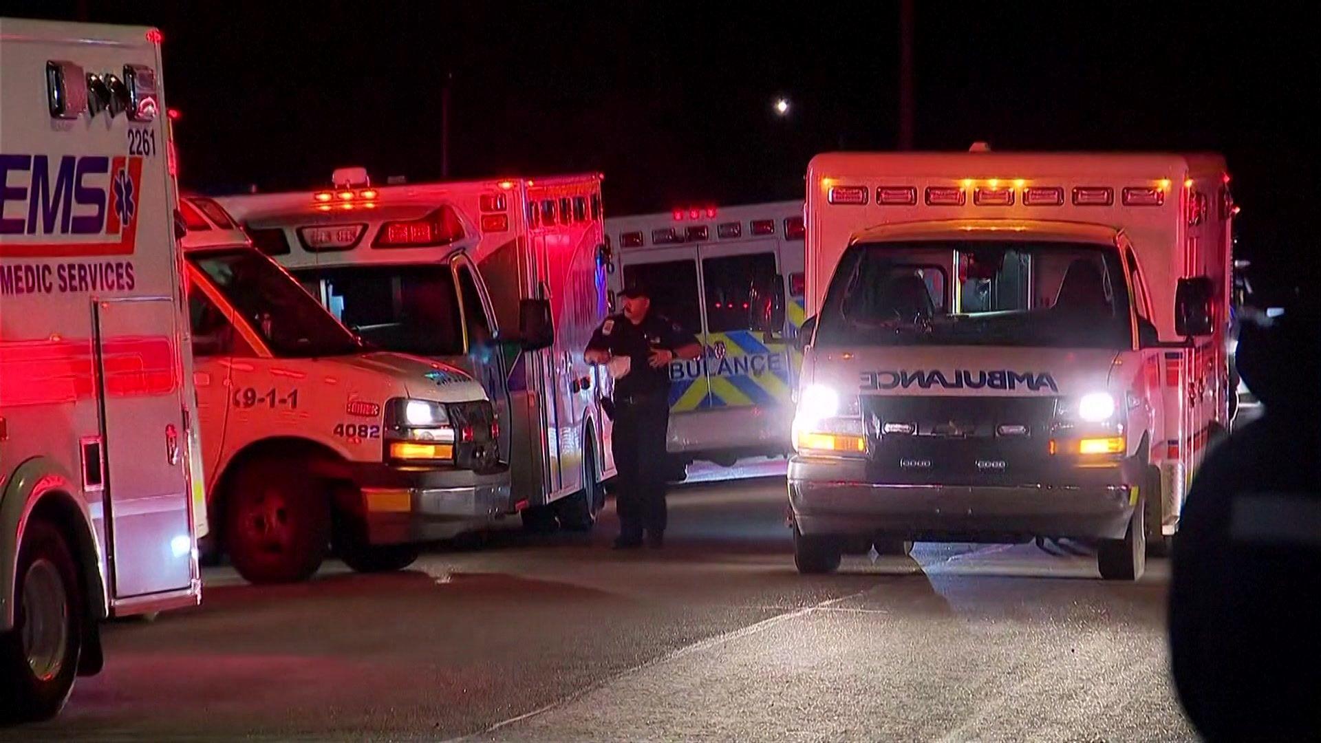 Ambulances line Wainwright health centre after the deadly blast at Canadian Forces Base Wainwright. Five emergency medical vehicles can be seen with their lights on, glowing red in the darkness. A man in uniform can be seen in the background.