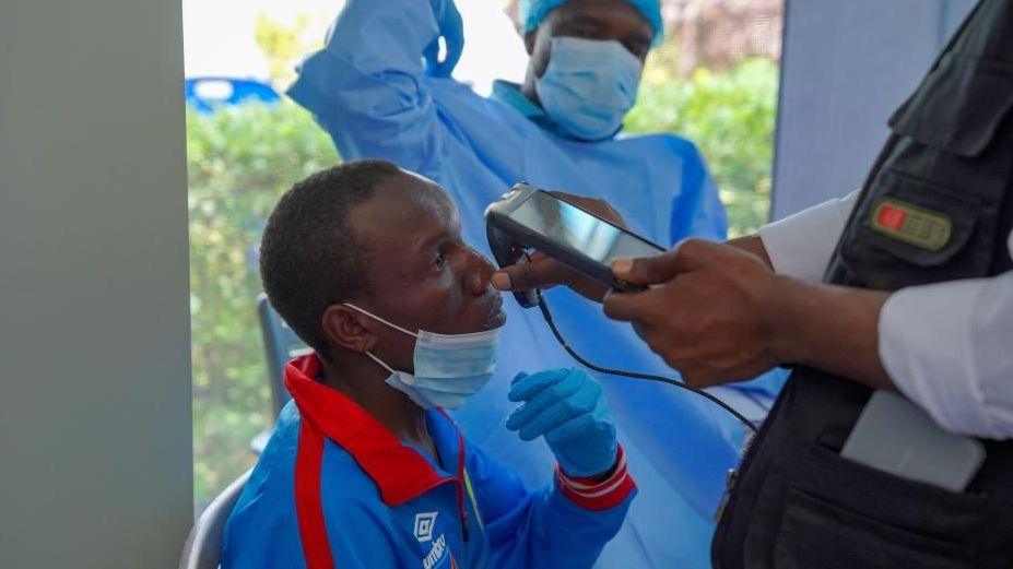 A man getting checked by a health professional who holds an implement up to him