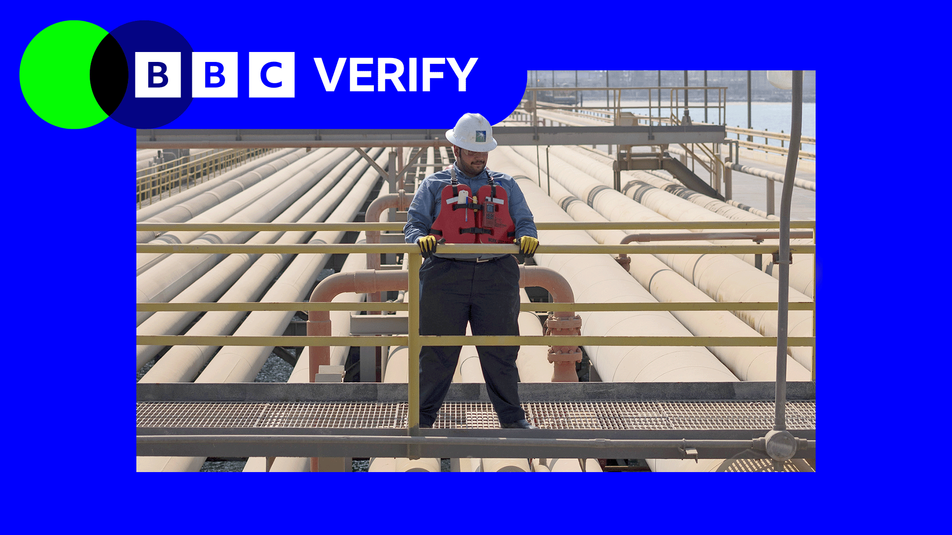 An oil worker stands near pipes