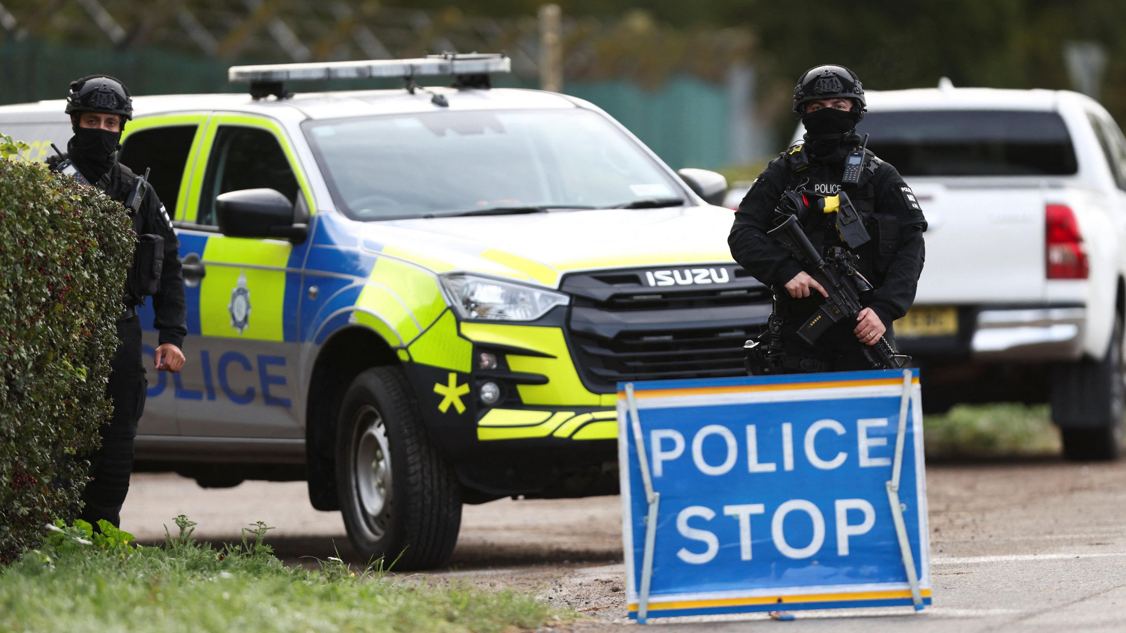 An armed police officer stands guards on a road outside the perimeter of the RAF Fairford airbase
