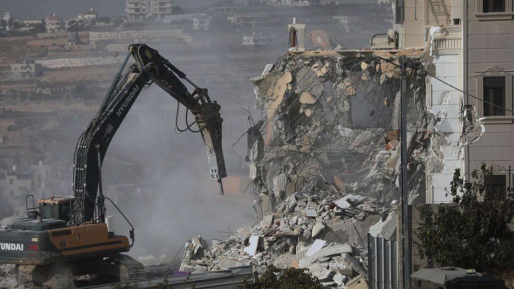 Digger destroys house. Rubble, dust and concrete.