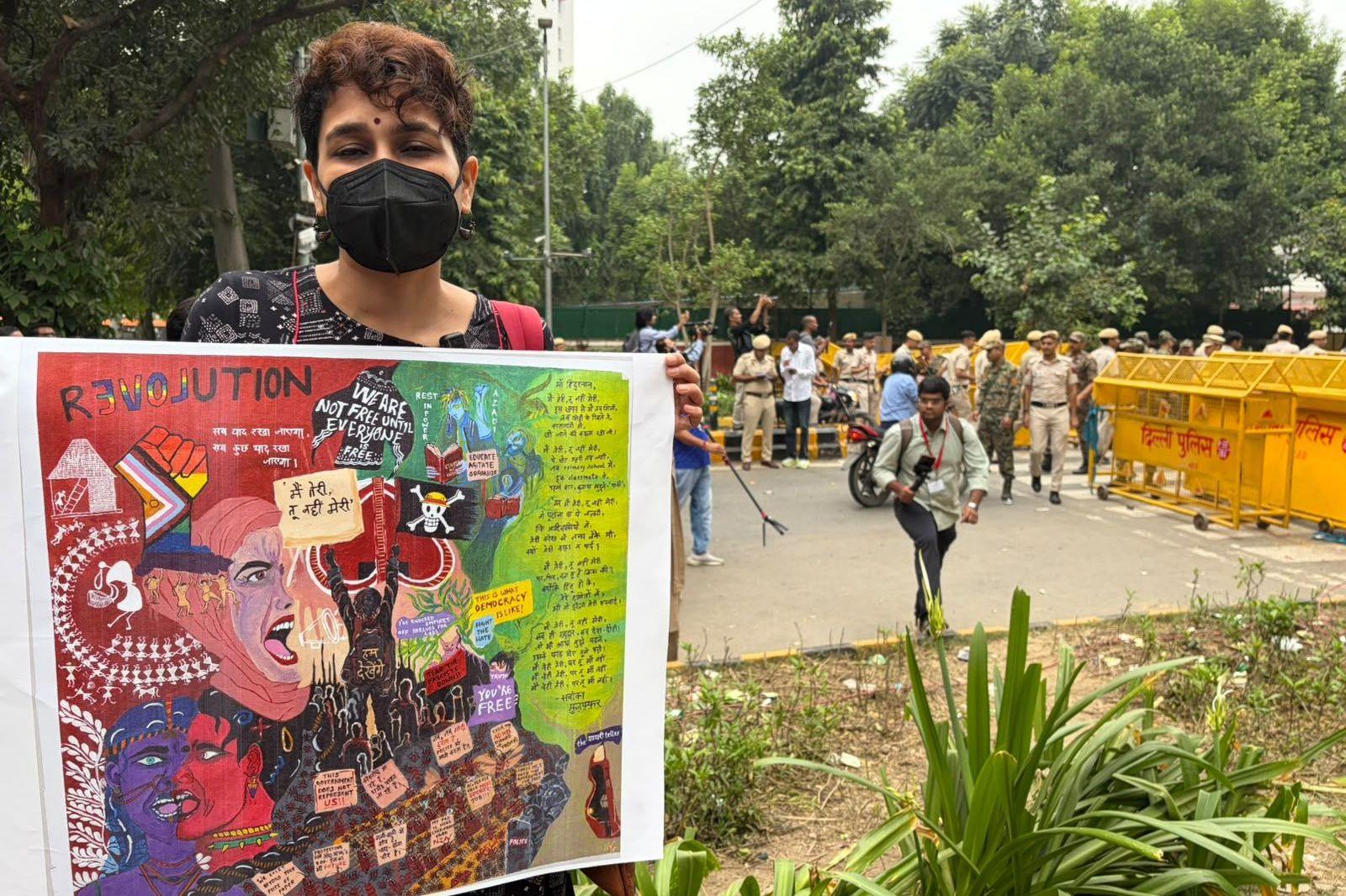 A protester holding a placard stands near the barricades in Delhi