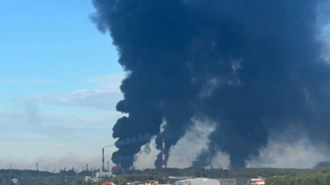 Thick black smoke billows into the sky above an industrial area