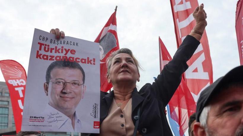 A supporter of the main opposition Republican People's Party (CHP) holds a poster featuring a picture of jailed Istanbul Mayor Ekrem Imamoglu and a slogan "CHP will succeed, Turkey will win"