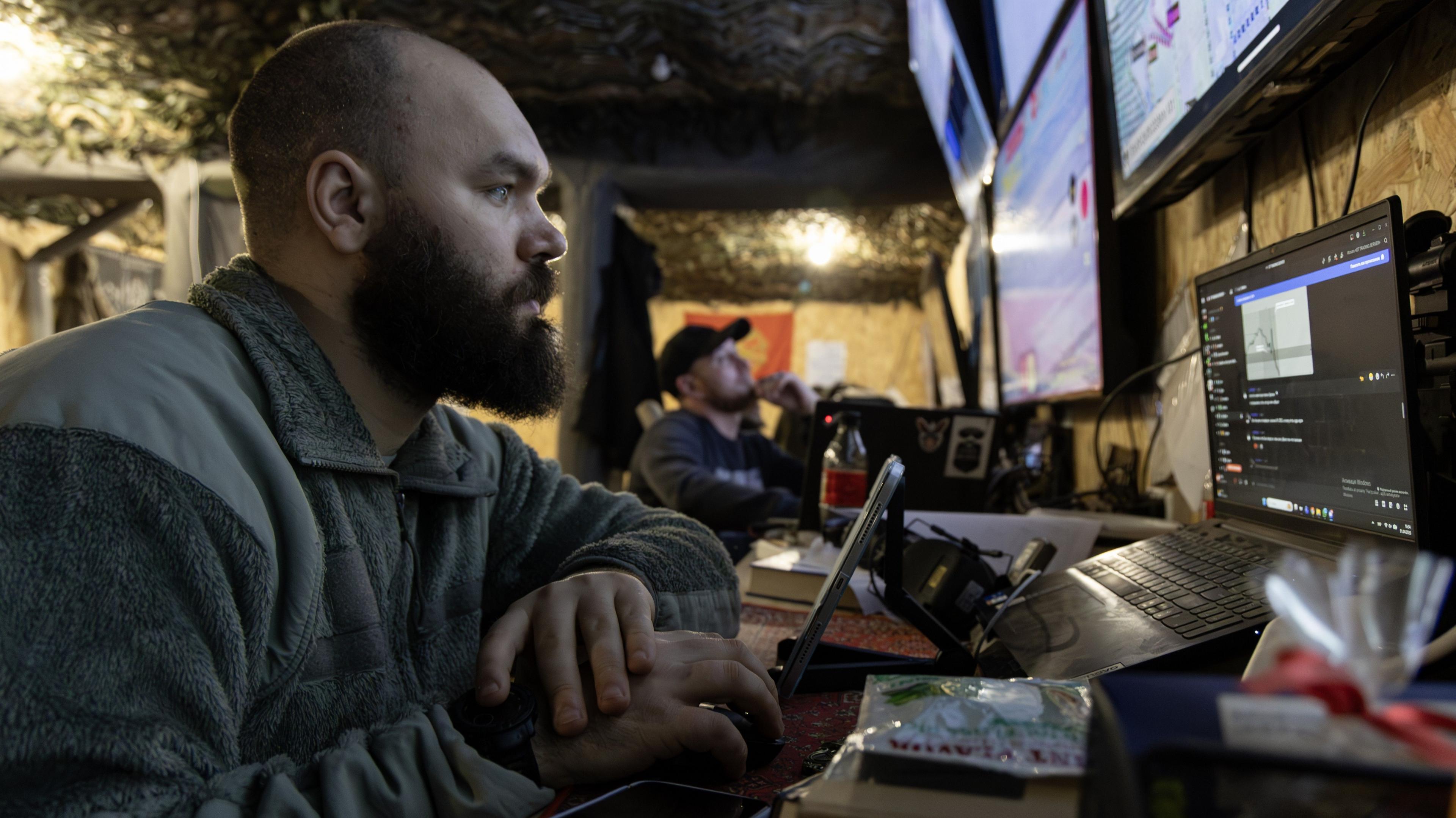 A close up of a Ukranian soldier surrounded by computer screens